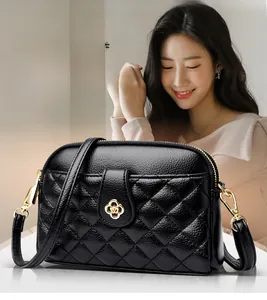 Detail of black quilted leather shoulder bag with gold floral clasp and adjustable strap
