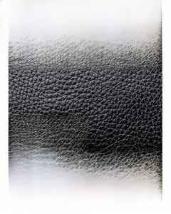 Close-up of black oil wax leather texture with quilted stitching on crossbody bag