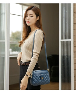 Detail of navy quilted leather crossbody bag with golden floral clasp on female model