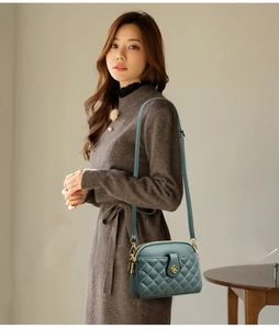 Detailed view of dark green quilted crossbody bag with gold floral clasp and leather strap
