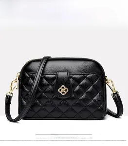 Close-up of black quilted leather with a gold clover clasp and lychee texture