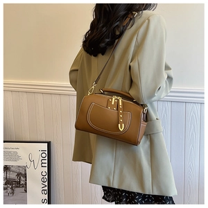 Vue détaillée du sac en cuir marron avec surpiqûres sur un blazer vert pastel