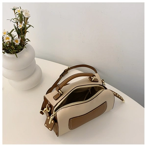 Détail d'un sac Boston bicolore beige et marron avec finitions dorées et poignées rondes