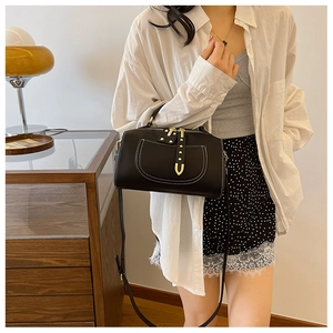 Détail du sac bandoulière noir avec coutures blanches et boucle dorée en U