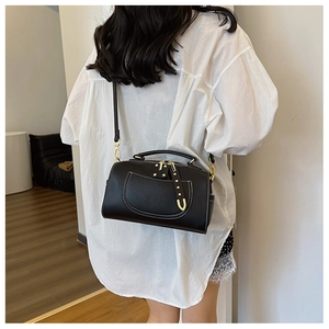 Détail du sac bandoulière noir avec surpiqûres blanches porté par un mannequin