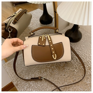 Détail du sac Boston bicolore beige et marron avec rivets dorés et finitions métalliques
