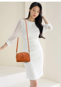 Orange lychee leather crossbody bag styled with a white dress for an elegant summer look