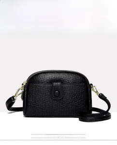 Close-up of black shell-shaped crossbody bag with gold hardware and wrinkled leather texture
