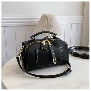 Sac Boston noir classique avec détails dorés et surpiqûres blanches sur marbre
