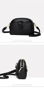 Detail of black crossbody bag featuring dual zippers and premium lychee texture leather