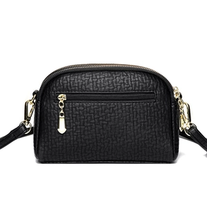 Minimalist black pebbled leather crossbody bag with golden hardware on white background