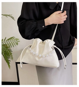 Detail of white pleated cloud bag with pearl beaded handle and matching leather strap