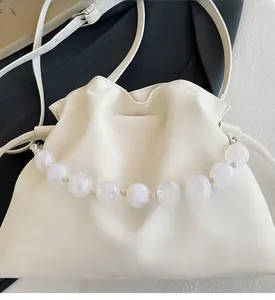 Detailed macro of white pleated cloud bag with marble bead handle on black fabric