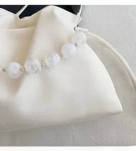 Close-up of white cloud bag featuring soft synthetic leather and large beaded strap detail