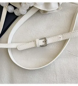 Detail of white leather shoulder strap with silver metal buckle and marble beads