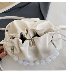 Detail of white pleated cloud bag showing drawstring closure and large pearl handle