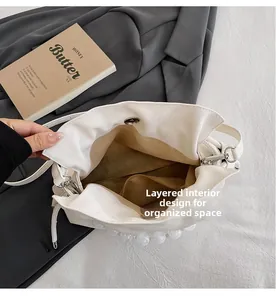 Interior view of white pleated handbag showing multiple compartments and zipper pocket