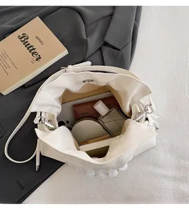 Detailed view of white pleated cloud bag interior showing spacious storage and pearl handle