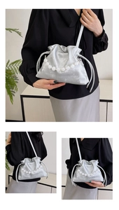 Detail of silver silk bucket bag with large white pearl handle and drawstring closure