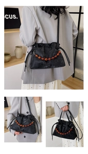 Detail of amber beaded chain and pleated cloud bucket bag with crossbody strap