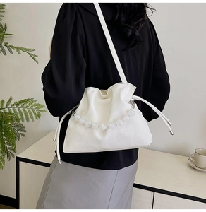 Close-up of white drawstring bucket bag with elegant pearl handle and soft leather texture