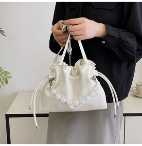 Detail of white beaded bucket bag with elegant faux leather and drawstring closure
