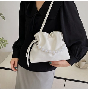 Detail of white pleated cloud bucket bag with pearl handle and long strap on model