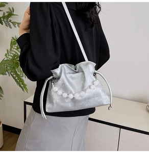 Detailed view of silver pleated drawstring bucket bag with elegant oversized pearl handle