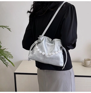 Detail of silver metallic pleated bucket bag with decorative pearl handle and strap