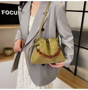 Close-up of avocado green cloud bucket bag with wooden beaded handle and drawstring detail