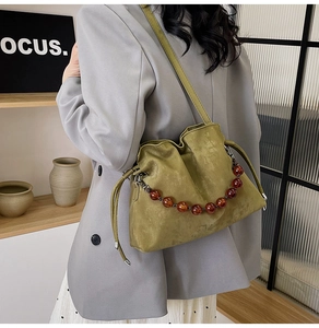 Close-up of green suede cloud bag with resin beads and adjustable shoulder strap