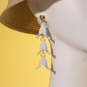 Détail de longues boucles d'oreilles blanches avec cœurs dorés et pétales en cascade