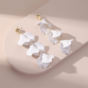 Détail macro de boucles d'oreilles pétales blancs avec clous en cœur dorés