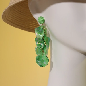 Vue détaillée de longues boucles d'oreilles pétales verts avec chapeau de paille