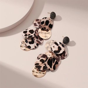 Détail de longues boucles d'oreilles bohèmes avec imprimé léopard et disques dorés martelés
