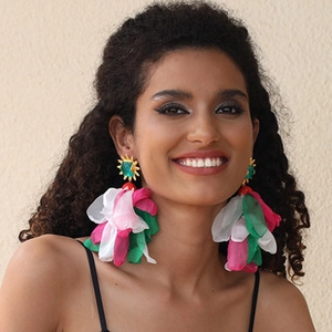 Close-up of bohemian floral earrings with pink and green fabric petals on a model