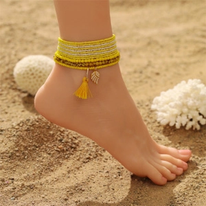 Bohemian colorful seed bead anklet set with yellow tassel and feather charm on the beach
