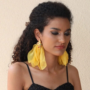 Macro shot of oversized yellow organza flower earrings with jeweled gold seashell studs