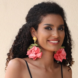 Detail of oversized pink lace flower earring with a gold pearl stud on a model