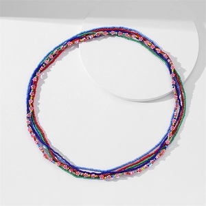Detail of colorful African waist beads with white floral accents on a white background