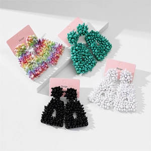 Macro shot of colorful beaded trapeze earrings with textured beadwork and designer cards