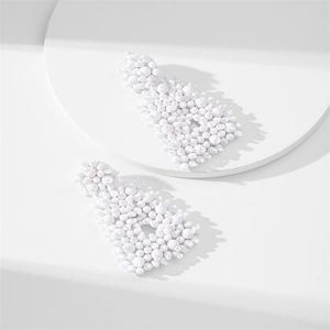 Close-up of handmade white beaded earrings featuring a minimalist geometric triangle design