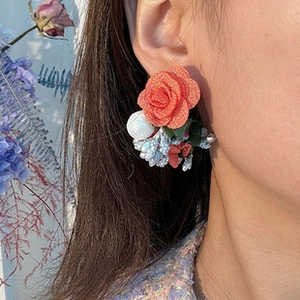 Gros plan de boucles d'oreilles fleurs en tissu avec perles et rose en textile orange