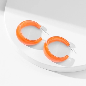 Detail of orange acrylic C-shaped earrings with marble texture on white display