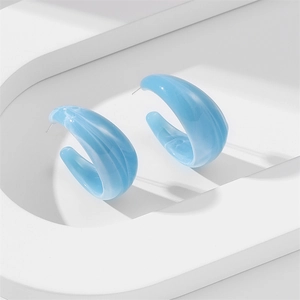 Macro detail of blue marble texture on C-shaped resin earrings with polished finish