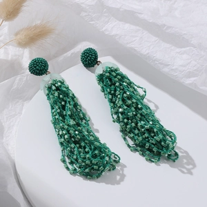 Detailed close-up of green bohemian seed bead tassel earrings on white background