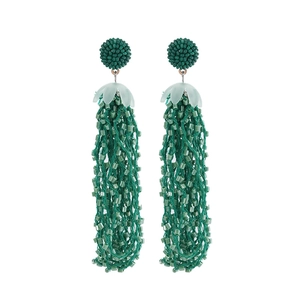 Macro shot of green beaded tassel earrings with bohemian woven details and floral caps