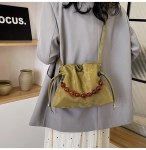 Detail of green suede bucket bag with amber beaded handle and drawstring closure