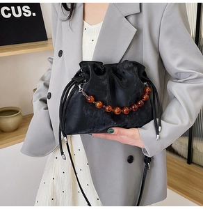 Detail of black pleated cloud bag with amber beads and slim leather shoulder strap