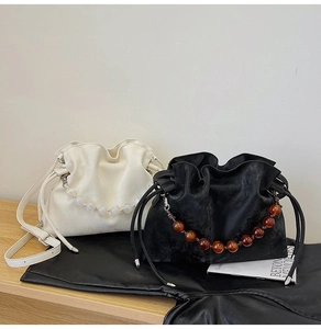 Detail of beaded handle bucket bags in cream and black with drawstring closure